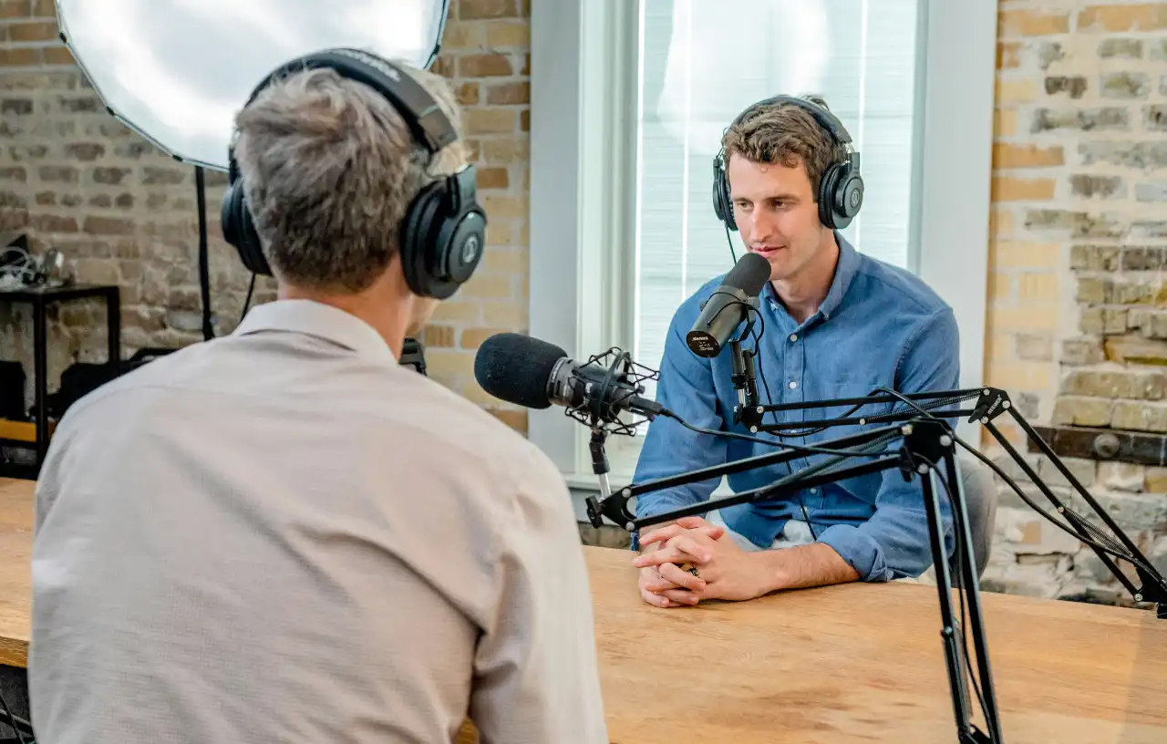 Two men recording a podcast interview with studio microphones and headphones
